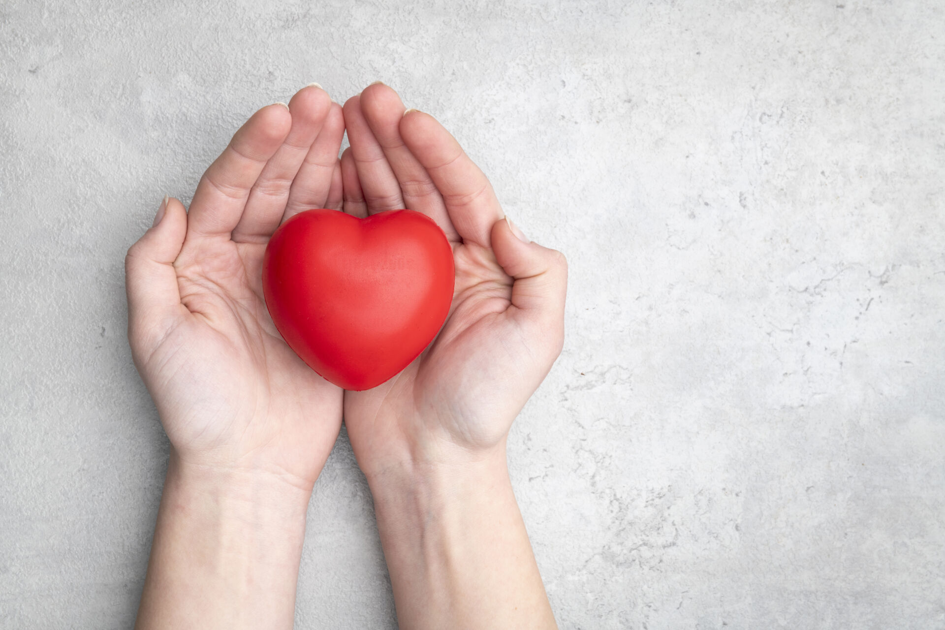 Red heart holding in female hands